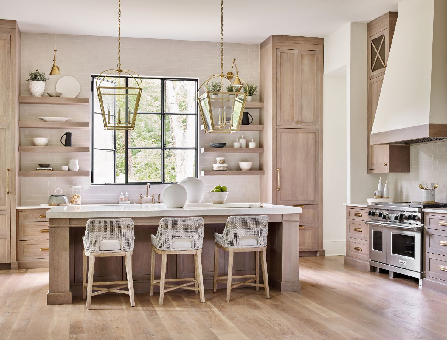 Photo of an open plan kitchen in light tones with wood and gold accents by Linen and Flax Co.